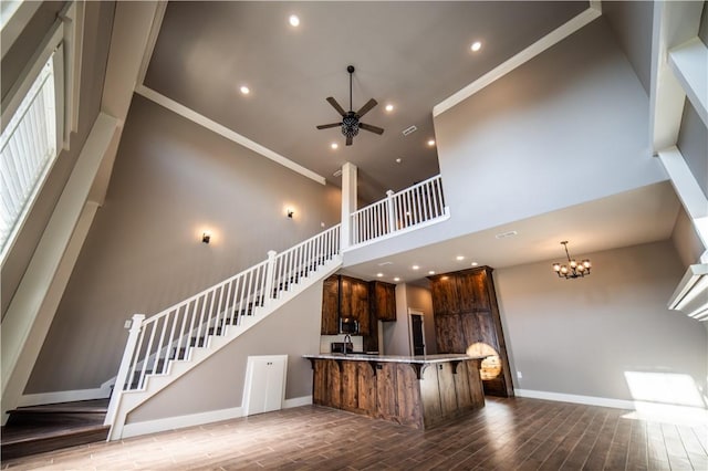 kitchen featuring kitchen peninsula, crown molding, ceiling fan with notable chandelier, and a high ceiling