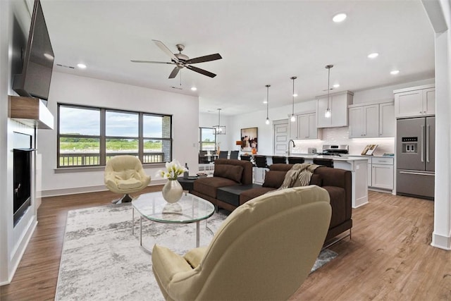 living room featuring hardwood / wood-style floors, ceiling fan, and sink