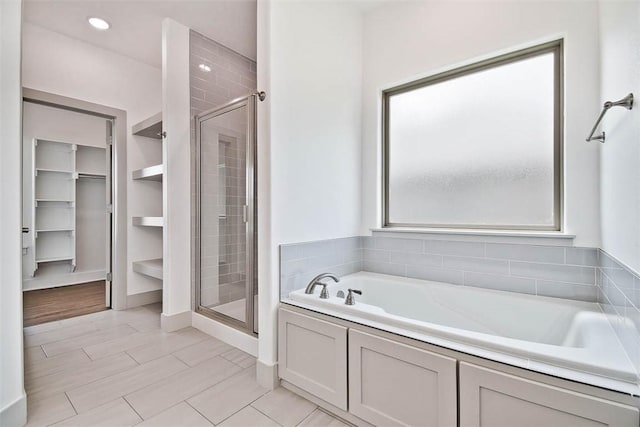 bathroom featuring shower with separate bathtub and built in shelves