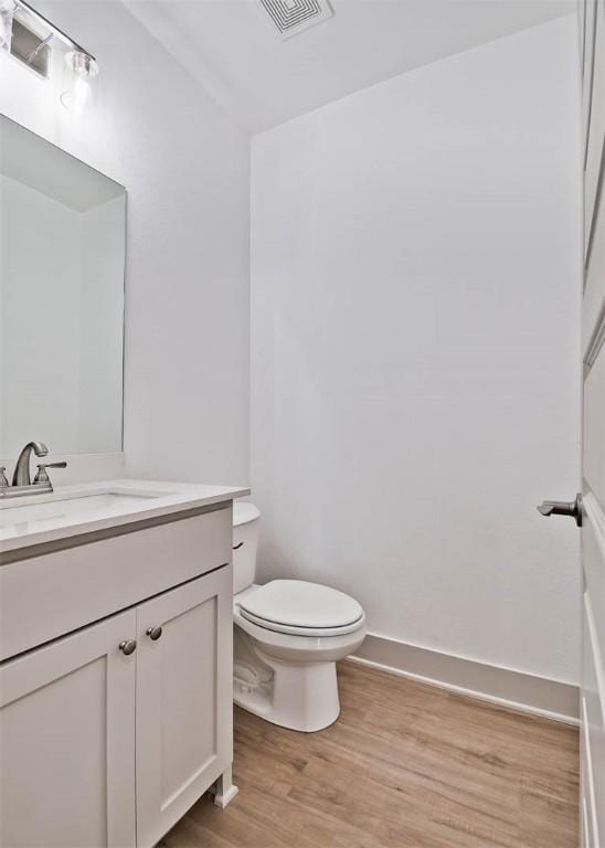 bathroom featuring vanity, wood-type flooring, and toilet