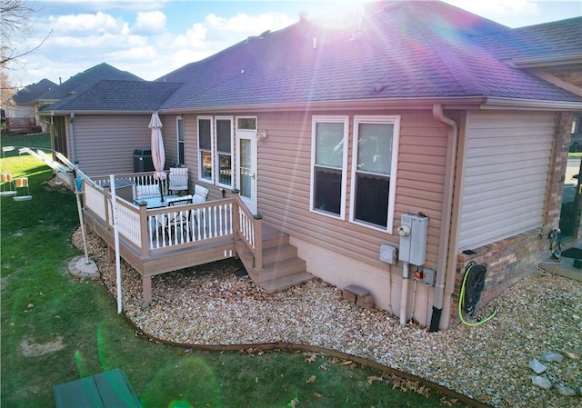 back of house featuring a lawn and a deck