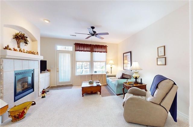 living room with a tile fireplace and ceiling fan