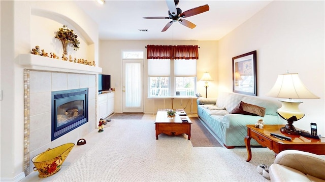 carpeted living room featuring a tile fireplace and ceiling fan