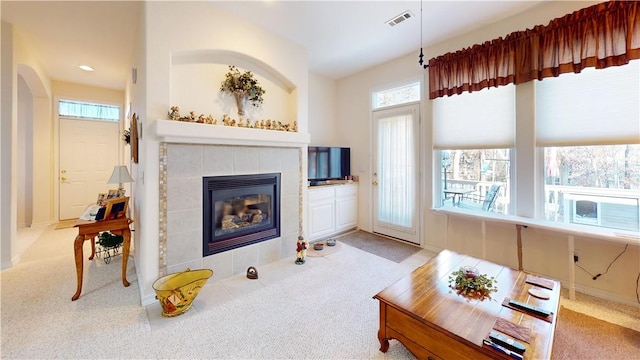 living room featuring a tile fireplace and light colored carpet