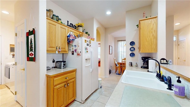 kitchen with tasteful backsplash, white fridge with ice dispenser, light tile patterned flooring, and sink