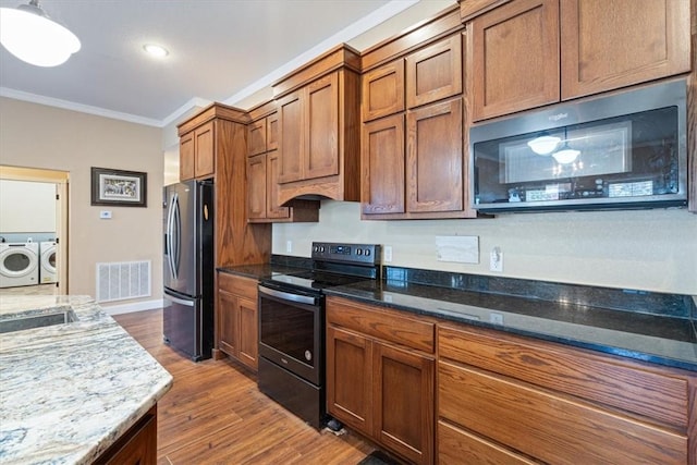 kitchen featuring black range with electric stovetop, light stone countertops, separate washer and dryer, stainless steel fridge, and hardwood / wood-style flooring