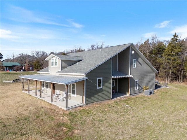 back of property featuring a lawn, central air condition unit, and a patio