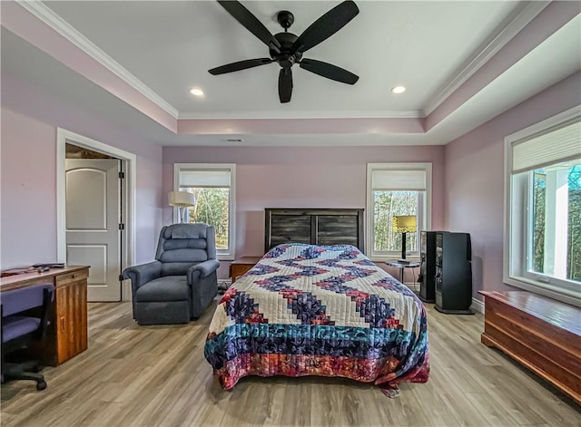 bedroom featuring ornamental molding, a tray ceiling, ceiling fan, and light hardwood / wood-style floors