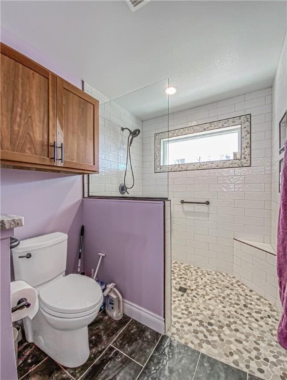 bathroom featuring tiled shower and toilet