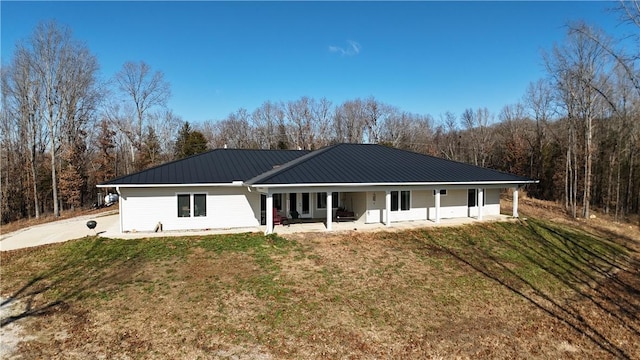 rear view of property featuring a lawn and covered porch