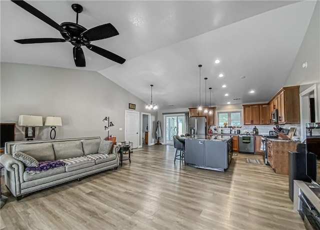 living room featuring ceiling fan with notable chandelier, light hardwood / wood-style flooring, and lofted ceiling