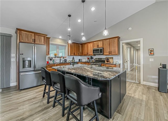 kitchen featuring backsplash, hanging light fixtures, stainless steel appliances, and dark stone counters