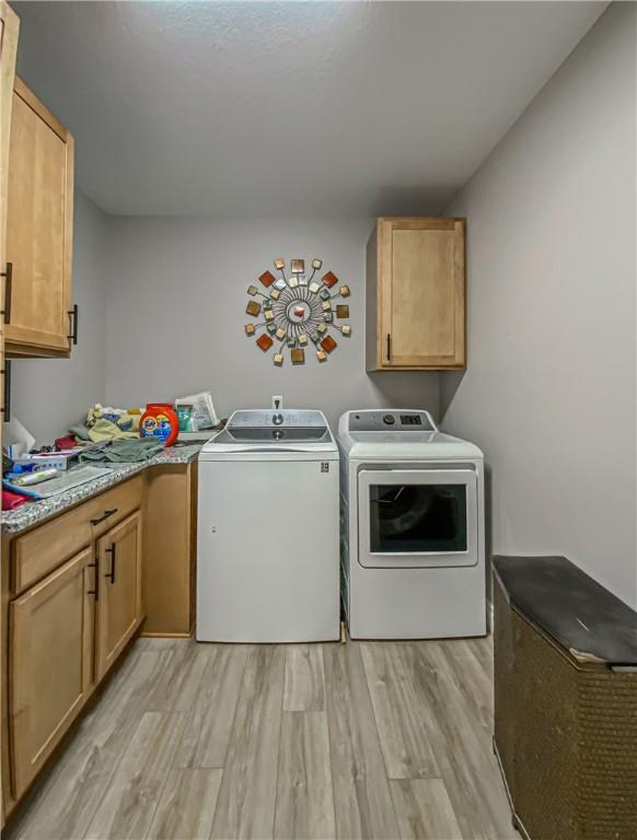 laundry area featuring cabinets, light wood-type flooring, and washer and clothes dryer