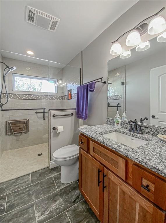 bathroom with vanity, toilet, and a tile shower