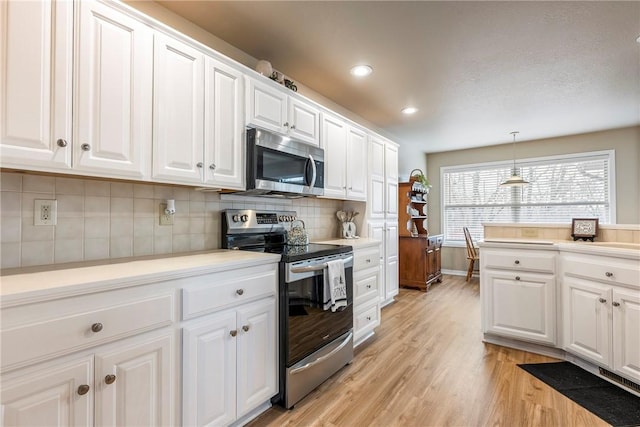 kitchen with white cabinetry, hanging light fixtures, stainless steel appliances, backsplash, and light hardwood / wood-style floors