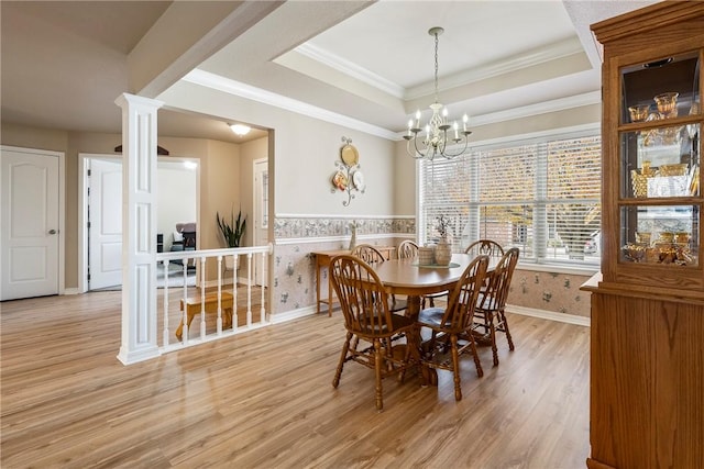 dining space featuring light wood-type flooring, ornate columns, a tray ceiling, crown molding, and a chandelier