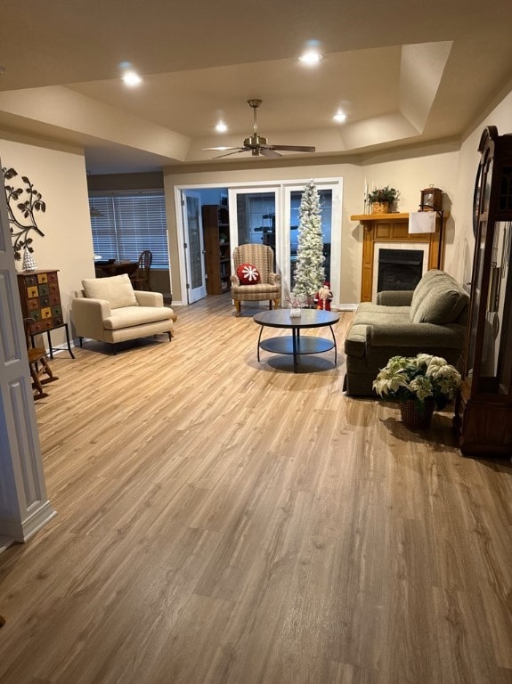 living room with hardwood / wood-style floors, ceiling fan, and a tray ceiling