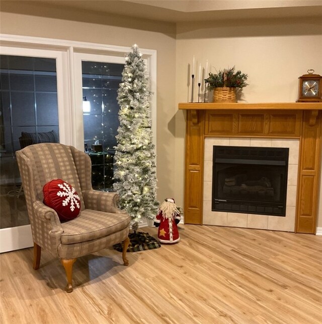 living area with a tile fireplace and light hardwood / wood-style flooring