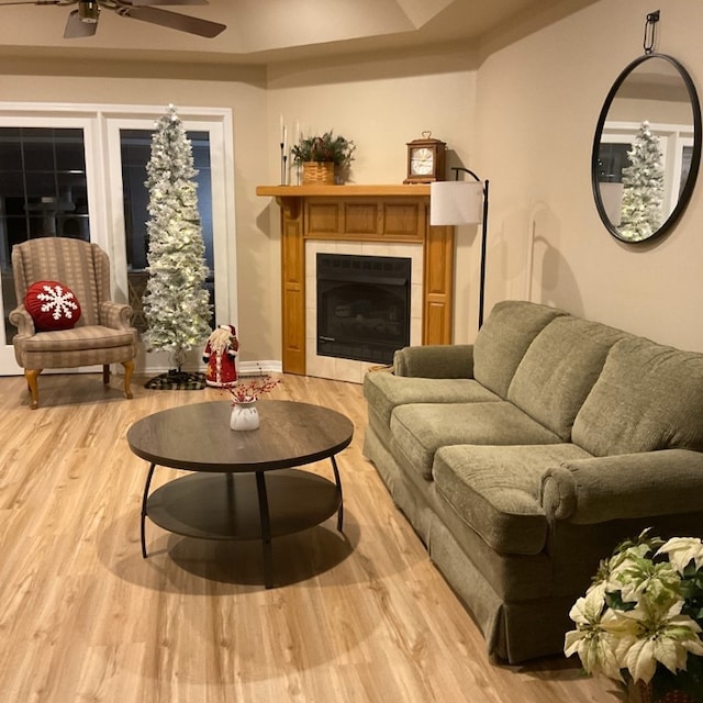 living room with ceiling fan, a fireplace, and light hardwood / wood-style floors