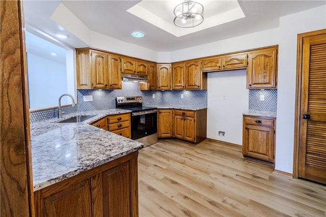 kitchen with stainless steel range with electric stovetop, a raised ceiling, sink, light hardwood / wood-style flooring, and light stone counters