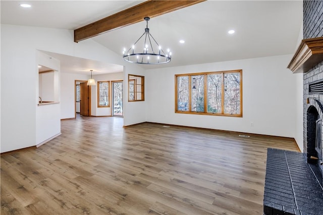 unfurnished living room with hardwood / wood-style floors, vaulted ceiling with beams, an inviting chandelier, and a brick fireplace