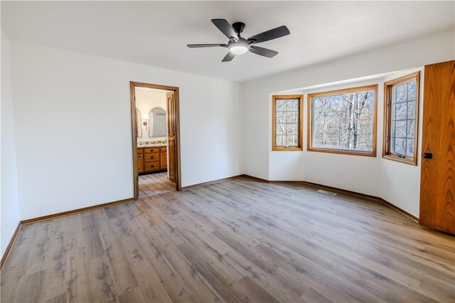 unfurnished bedroom featuring ceiling fan, light wood-type flooring, and connected bathroom