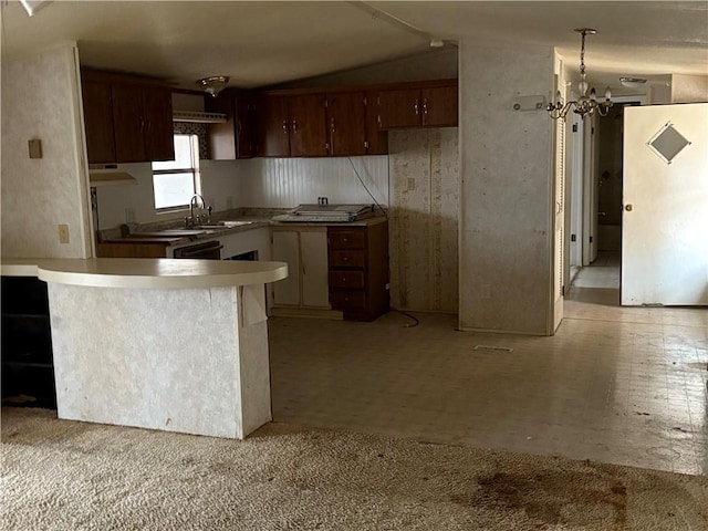 kitchen with kitchen peninsula, sink, white refrigerator, an inviting chandelier, and lofted ceiling