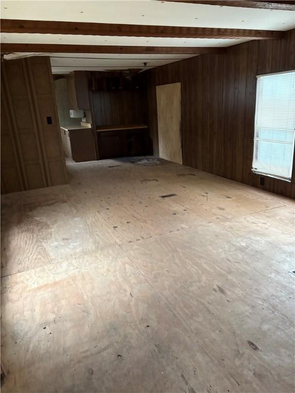 unfurnished room with beamed ceiling and wooden walls