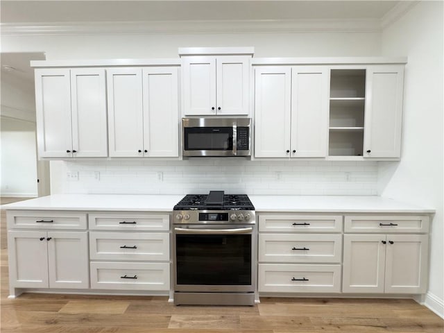 kitchen featuring light wood finished floors, stainless steel appliances, ornamental molding, and decorative backsplash