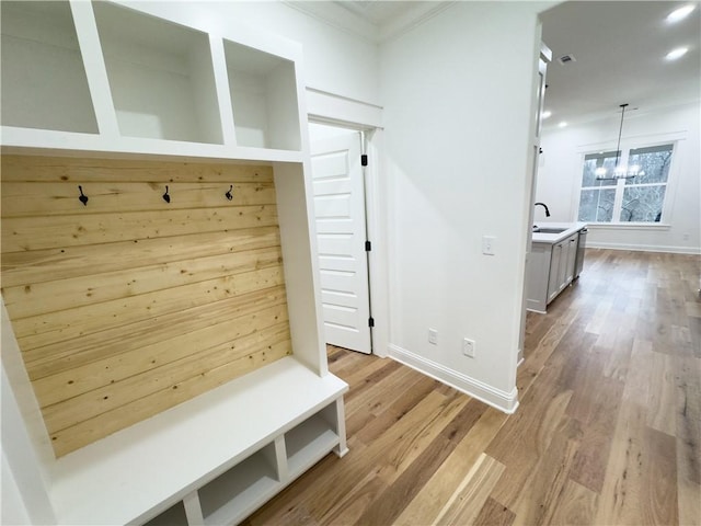 mudroom with a sink, a notable chandelier, baseboards, and wood finished floors