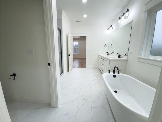 bathroom with marble finish floor, double vanity, a soaking tub, and baseboards