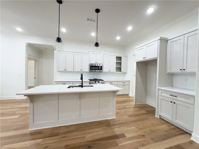 kitchen featuring appliances with stainless steel finishes, decorative backsplash, sink, white cabinets, and pendant lighting