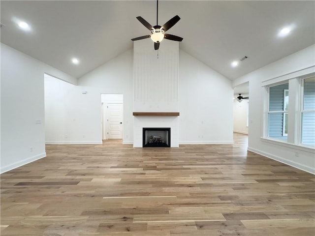 unfurnished living room featuring a fireplace, visible vents, ceiling fan, high vaulted ceiling, and light wood-type flooring