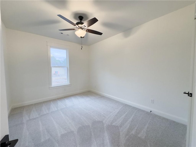 spare room with baseboards, visible vents, a ceiling fan, and light colored carpet