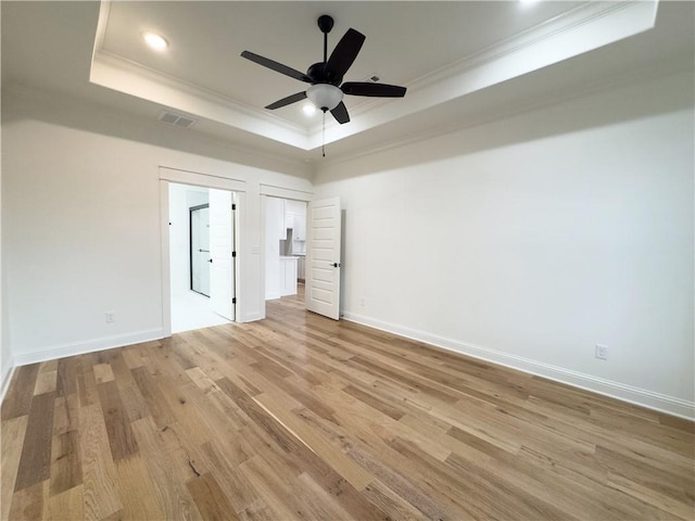 unfurnished bedroom featuring ceiling fan, light hardwood / wood-style floors, a tray ceiling, and ornamental molding