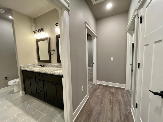 bathroom featuring wood-type flooring, vanity, and toilet