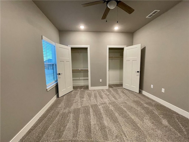 unfurnished bedroom featuring carpet flooring, multiple closets, and ceiling fan