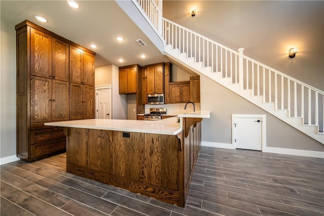 kitchen with a breakfast bar area, kitchen peninsula, sink, and appliances with stainless steel finishes