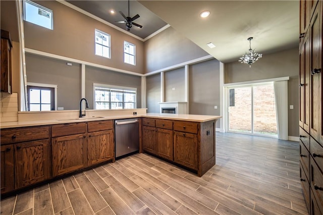 kitchen featuring kitchen peninsula, ornamental molding, sink, dishwasher, and light hardwood / wood-style floors