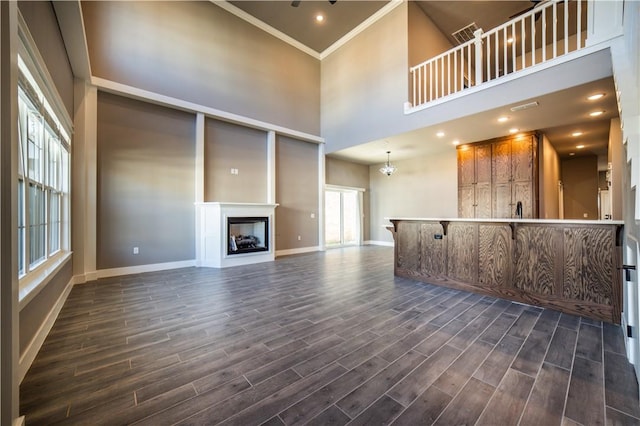 unfurnished living room featuring ornamental molding, a high ceiling, and a chandelier