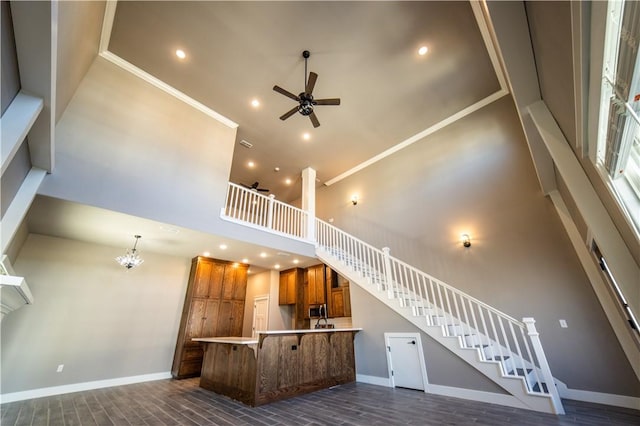 interior space with a towering ceiling, ceiling fan with notable chandelier, and ornamental molding