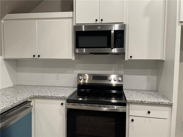 kitchen with light stone countertops, backsplash, stainless steel appliances, and white cabinetry