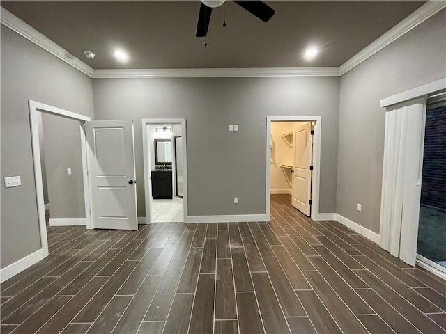 unfurnished bedroom with ceiling fan, a spacious closet, crown molding, and connected bathroom