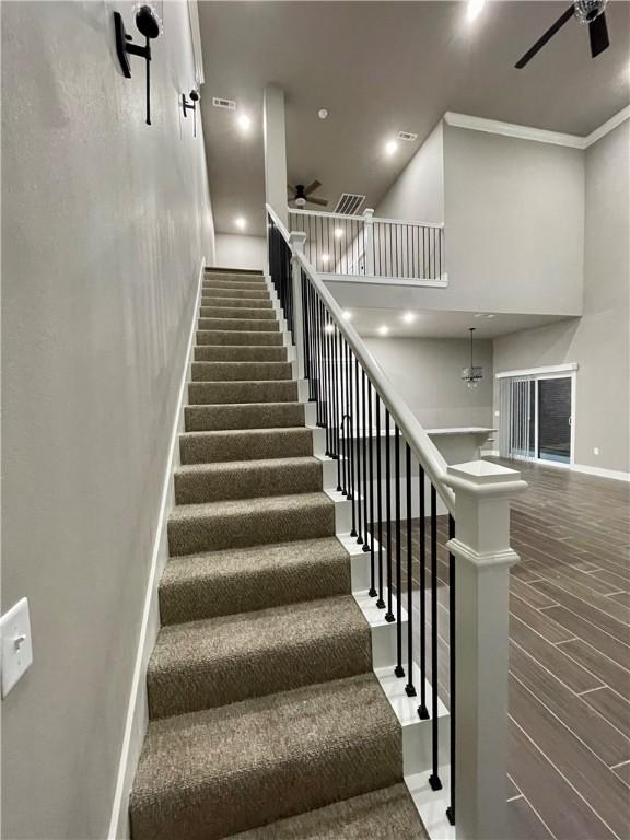 stairway featuring ceiling fan, hardwood / wood-style floors, and ornamental molding