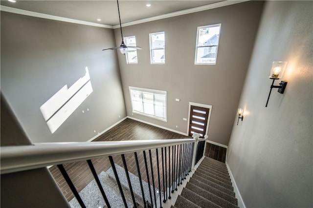 stairway with hardwood / wood-style floors, ceiling fan, and ornamental molding