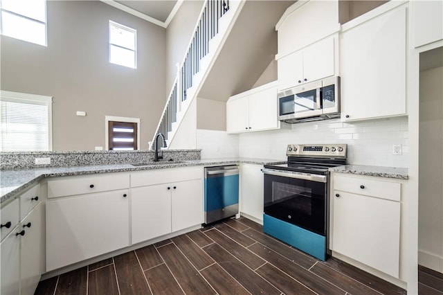 kitchen featuring white cabinets, light stone counters, sink, and stainless steel appliances