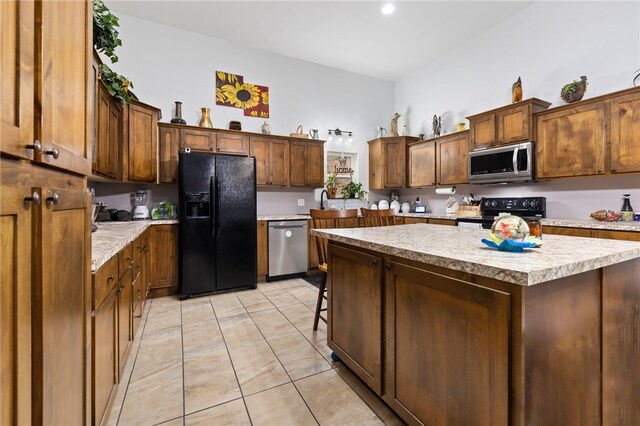 kitchen featuring black appliances, a kitchen island, a kitchen bar, and light tile patterned floors