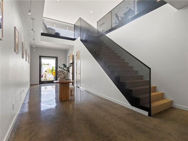 stairway with concrete flooring and a high ceiling