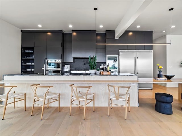 kitchen featuring extractor fan, dark cabinetry, stainless steel built in fridge, modern cabinets, and decorative light fixtures