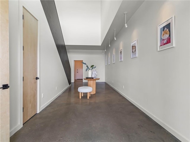 hall featuring concrete floors and baseboards